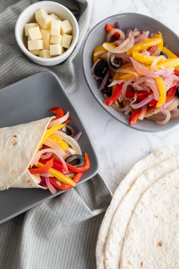 Roasted Pepper Trattoria Wrap next to bowl of onions and peppers