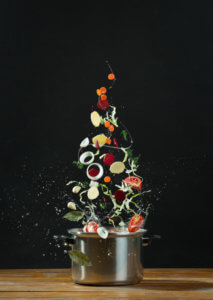 Vegetables on a black background  tossed into a pot