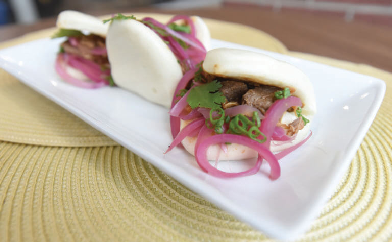 Bao Bun sandwich on white plate with pickled red onion