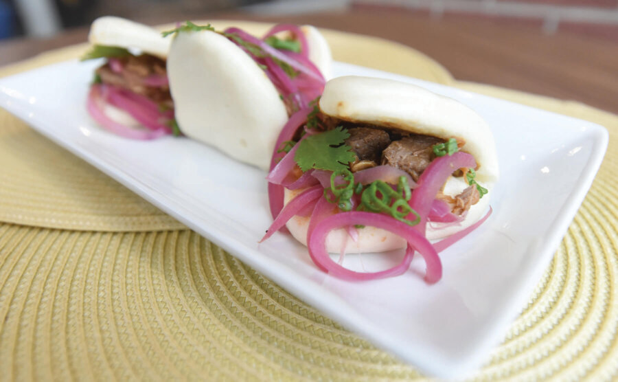 Bao Bun sandwich on white plate with pickled red onion