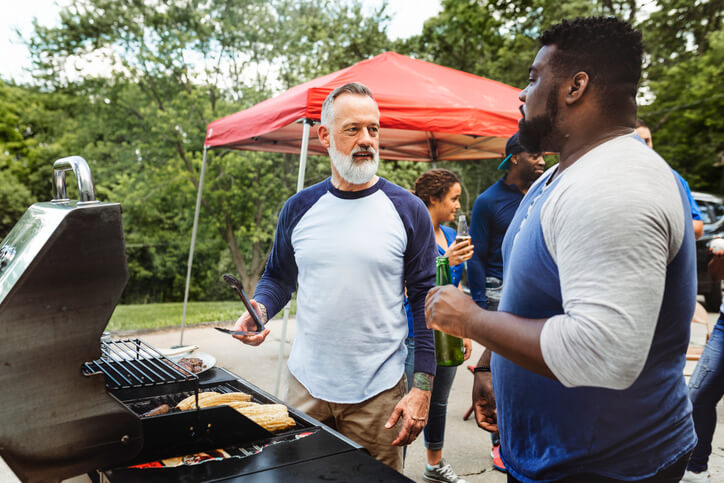 Two men manning the grill at a tailgate party