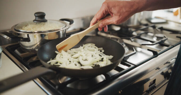 cooking sliced onions in a pan on a stove