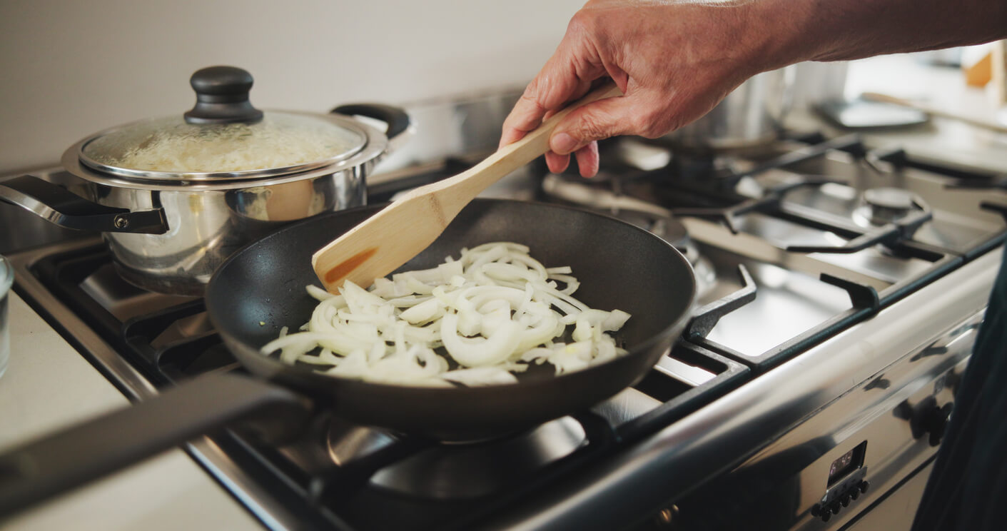 cooking sliced onions in a pan on a stove