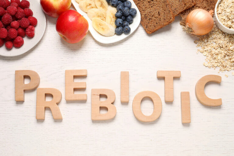 Flat lay composition with word Prebiotic made of wooden letters and different products on white table